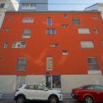 Wohnhaus mit orangener Fassade und kleinen Fenstern, Wien-Leopoldstadt