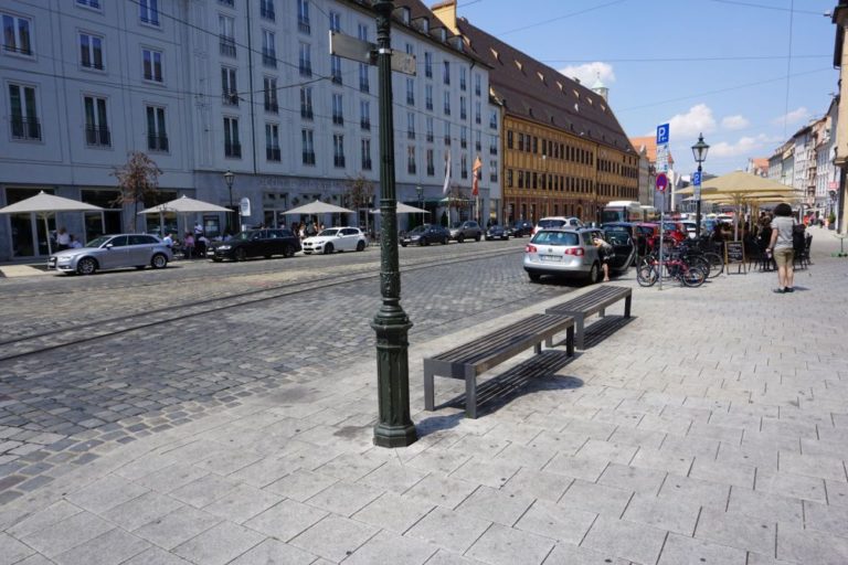 Straße mit historischen Gebäuden und Pflastersteinen in Augsburg, Straßenlaternen, Autos