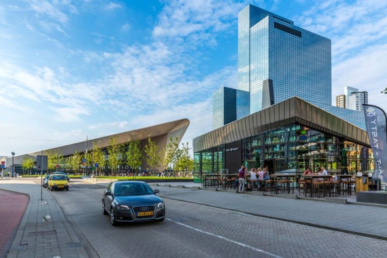 Rotterdamer Hauptbahnhof mit Hochhäusern und Auto
