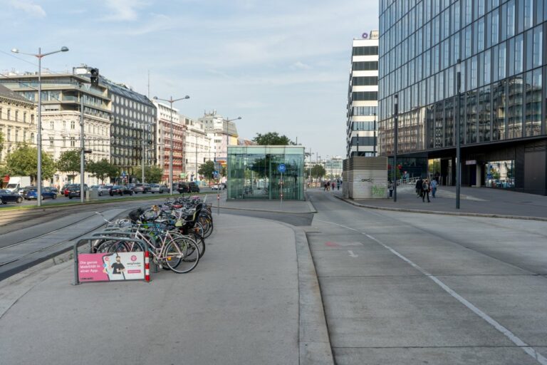 abgestellte Fahrräder, Bürohäuser, Radweg, Straßenbahnschienen, fahrende Autos, Gehsteig, Asphalt