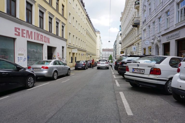 parkende Autos, fahrendes Auto und Radfahrer in der Otto-Bauer-Gasse, Wien-Mariahilf