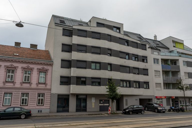 Neubau mit grau-gestreifter Fassade in Wien, Kagran, Donaustadt, neben Gründerzeithaus