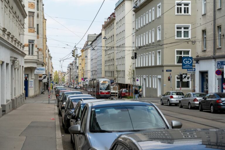 Straßenbahn fährt durch eine Straße, parkende Autos, Häuser, Fasanviertel