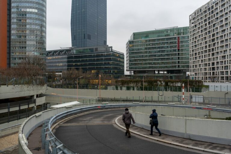 zwei Personen gehen auf einer Kurve einer Straße, Hochhäuser