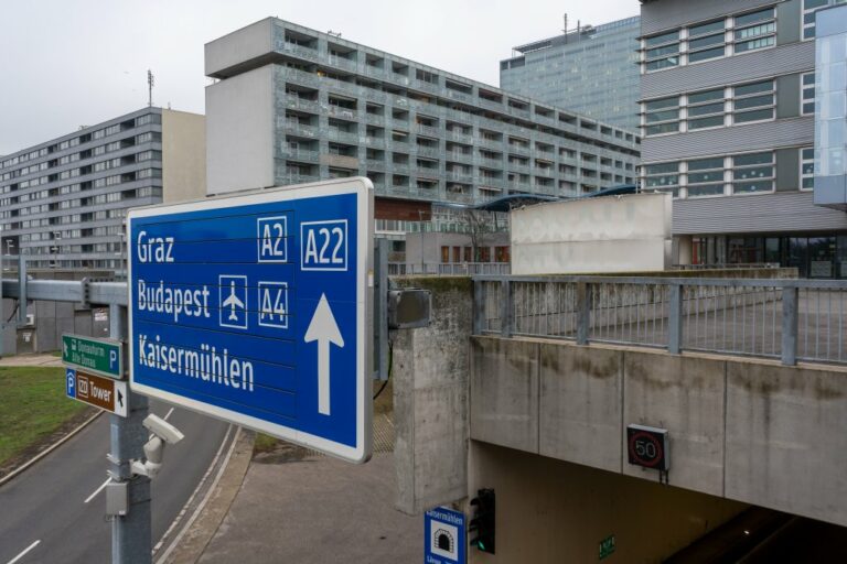 Wohnhäuser und Schule bei einem Autobahntunnel, großes Straßenschild