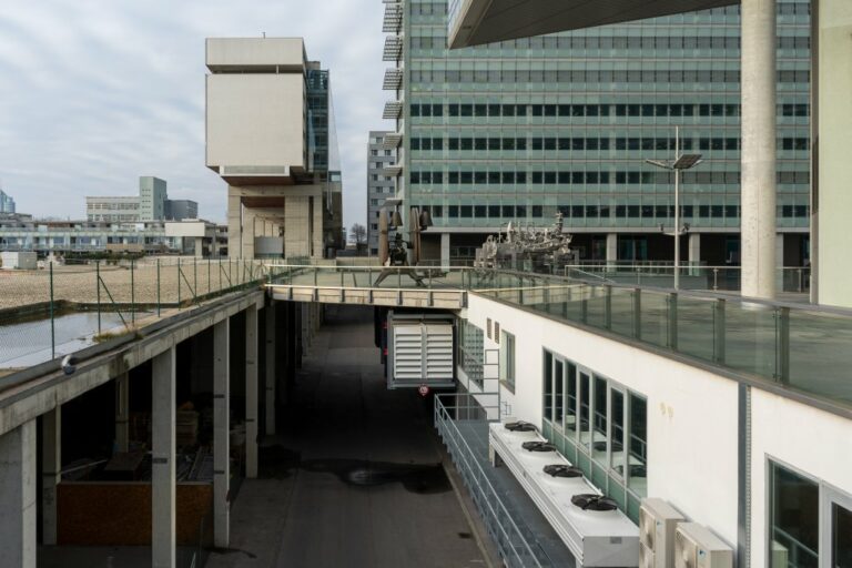 aufgeständerte Fußgängerebene, darunter Fahrbahnen für Kfz, Hochhaus mit Glasfassade, Kunstwerke