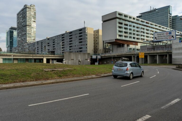 Auto fährt auf einer Straße vor Hochhäusern in Wien