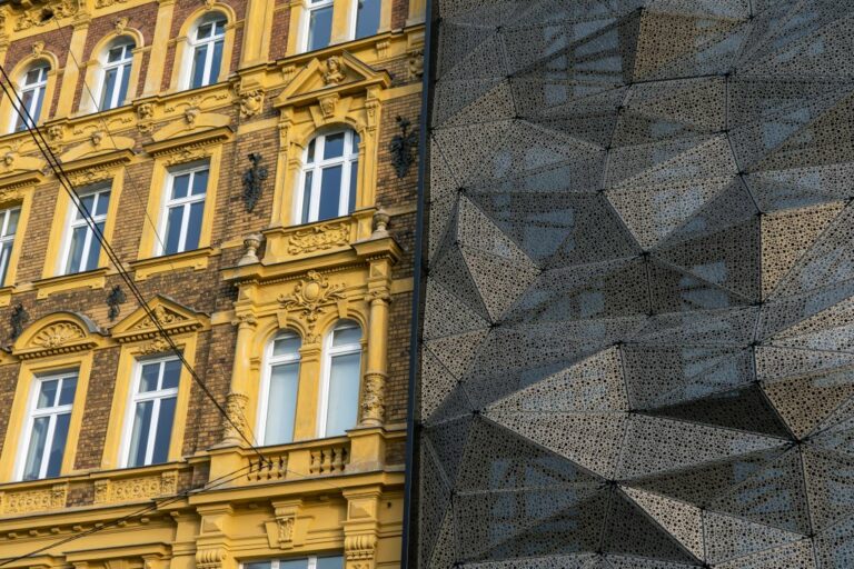 links ein Gebäude im Stil des Historismus mit geschmückter Fassade, rechts ein Neubau mit vorgelagerten Metallplatten