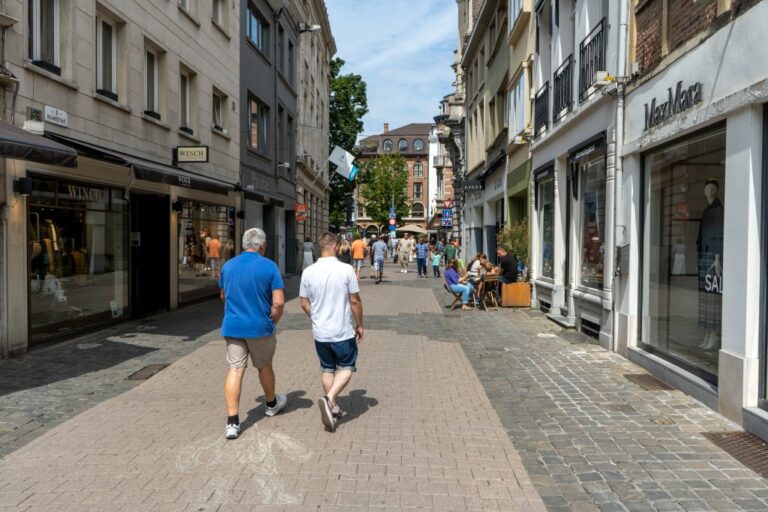 zwei Männer gehen durch eine Fußgängerzone, links und rechts Geschäfte