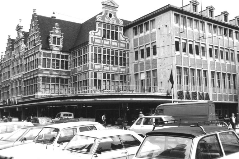 Autos parken vor einem Kaufhaus, links Altbauten, rechts neueres Gebäude, altes Foto