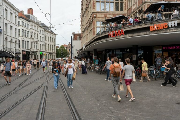 Leute gehen durch eine Fußgängerzone im Stadtzentrun von Gent, rechts ein Kaufhaus