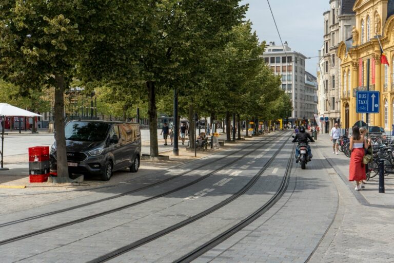 Platz in Gent, Motorradfahrer fährt am Rande des Platzes auf einer Fahrbahn mit Schienen