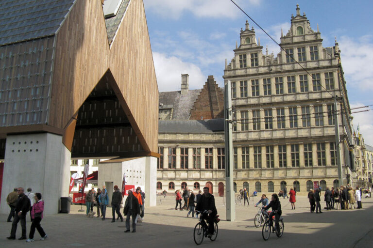 Radfahrer und Fußgänger im Stadtzentrum von Gent, moderne Halle neben altem Rathaus