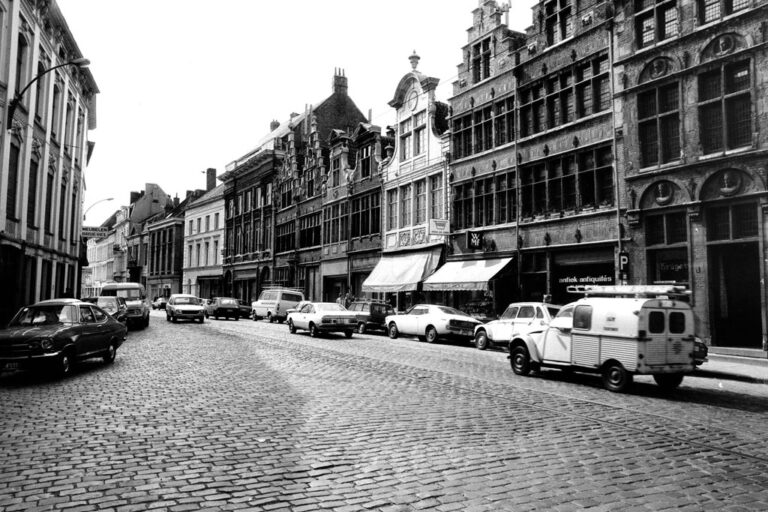 altes Foto einer Straße in Gent, Autos, schmale alte Häuser, Steinpflasterung, Straßenbahnschienen, Markisen