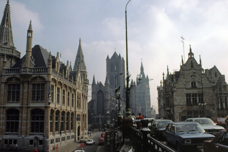 Sint-Michielsbrug, dichter Autoverkehr auf einer Brücke in Gent, links neugotisches Gebäude, Kirche und Belfried in der Mitte