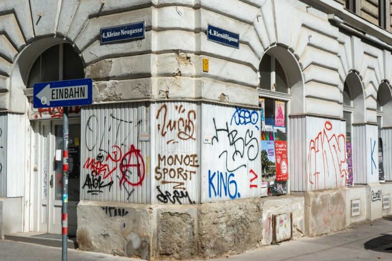 Erdgeschoßfassade des Gründerzeithauses an der Ecke Kleine Neugasse/Rienößlgasse mit beschädigtem Dekor und Graffiti, Einbahn-Schild