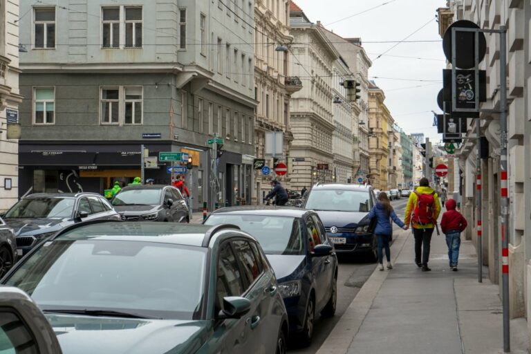 Erwachsene mit zwei Kindern geht auf einem Gehsteig in der Argentinier Straße