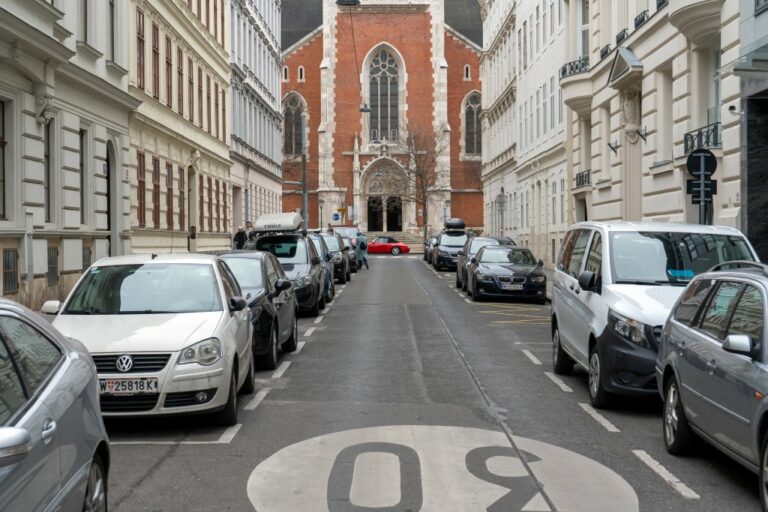 Straße mit parkenden Autos und alten Gebäuden, Kirche