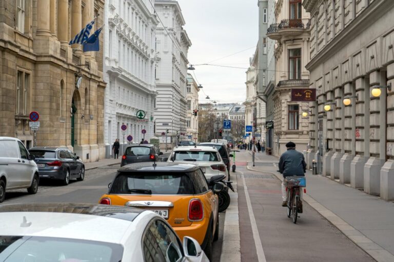 Radfahrer fährt auf einem Radweg zwischen parkenden Autos und Gehsteig in der Argentinierstraße, Griechische Botschaft