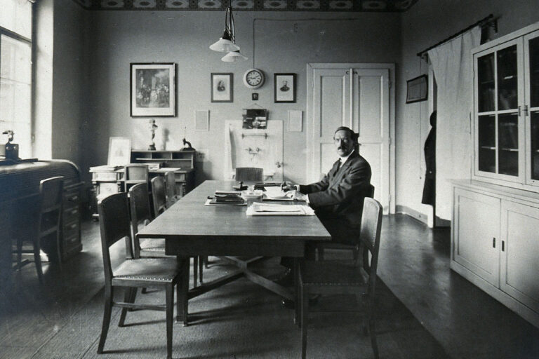Clemens von Pirquet sitzt am Tisch und schreibt, historische Aufnahme