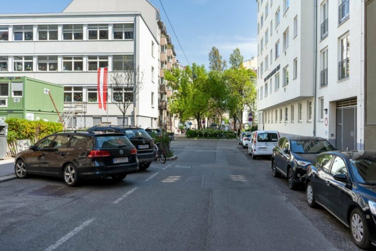 parkende Autos in der Pfeilgasse zwischen einer Schule und einem Wohnhaus