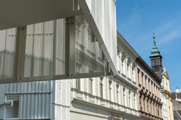 Neubau mit Blechfassade neben Altbauzeile und Kirchenturm