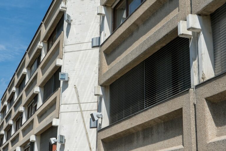 Fassade eines Bürohauses aus den 1960er-Jahren, mit Sichtbeton, Waschbeton, Rollos und Scheinwerfern