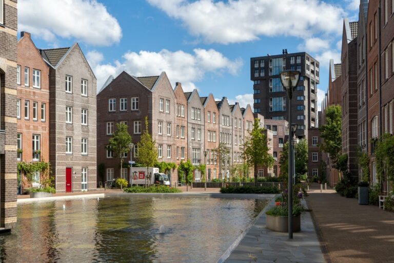 Wohnhäuser in Den Haag mit Wasserfläche in der Mitte, hinten ein Hochhaus