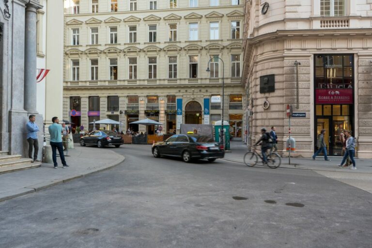 Autos und Radfahrer fahren an der Peterskirche vorbei, Fußgänger