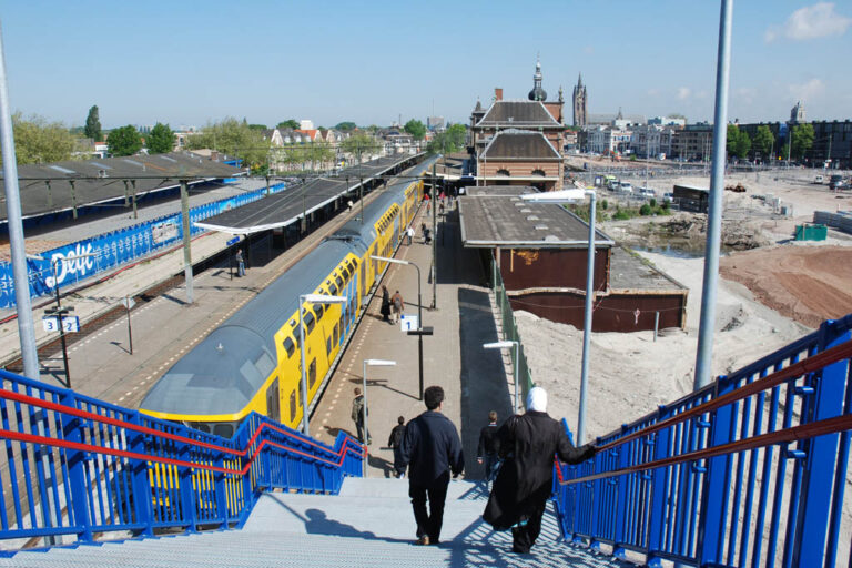 Bahnhof von Delft, Leute gehen Treppen hinunter zum Bahnsteig, Zug
