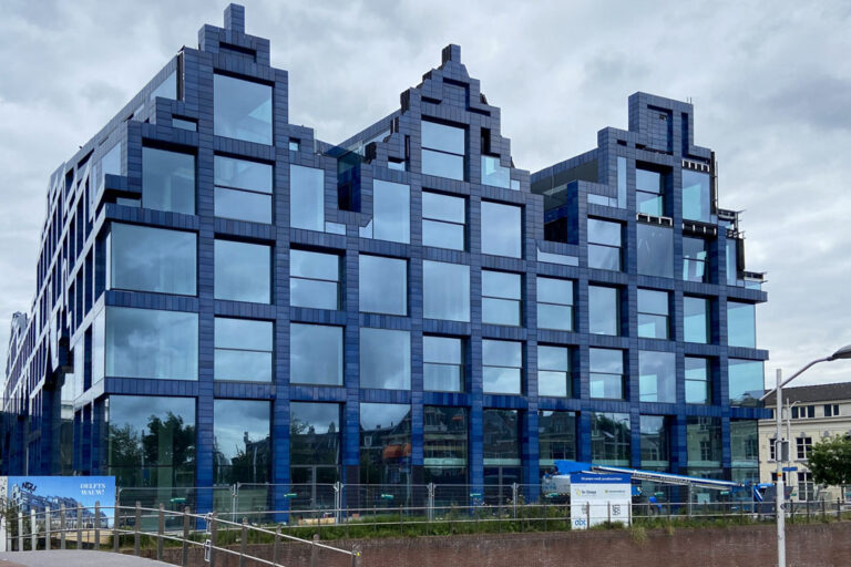 Neubau mit blauen Fliesen und großen Fenstern wird errichtet
