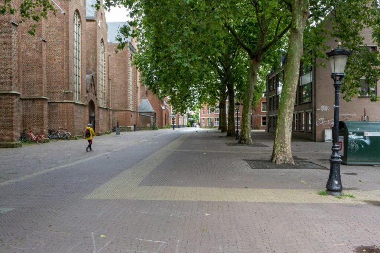Backsteinkirche, autofreier Platz, hohe Bäume