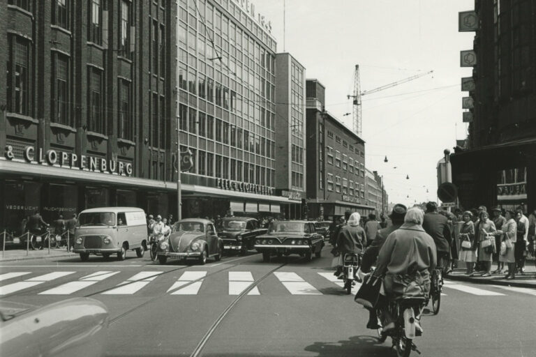 Radfahrer und Autoverkehr in einer Einkaufsstraße, Warenhäuser