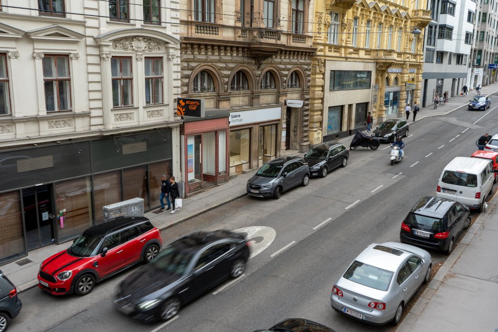 fahrende und parkende Autos in der Gumpendorfer Straße, alte Häuser, Fußgänger, Asphalt, Geschäfte