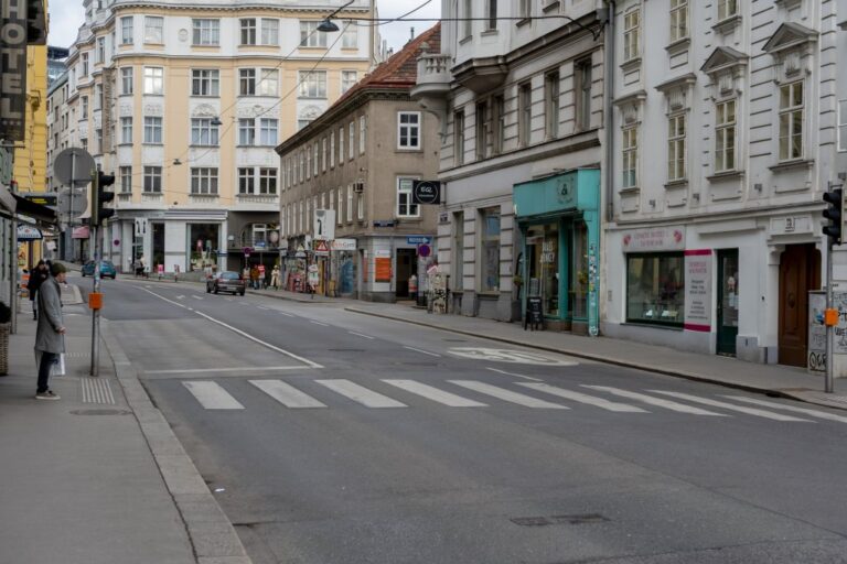 Straße im 6. Bezirk in Wien, Mann wartet an einer Ampel, Ensemble aus alten Häusern unterschiedlicher Baustile