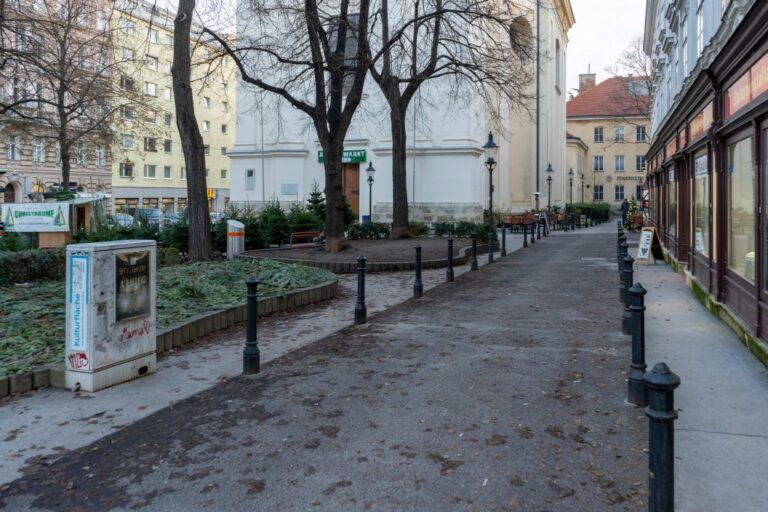 Platz vor einer Kirche in Wien, Fußgängerzone, Asphalt, Poller, Bäume, Schaltkasten