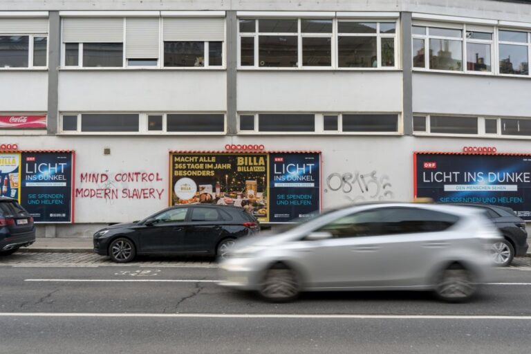 Auto fährt vor einem Gebäude mit Plakaten vorbei