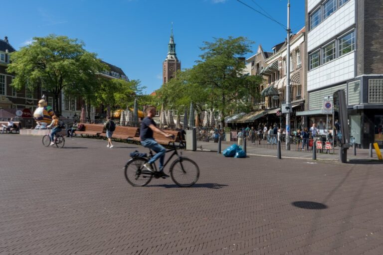 Person fährt auf einem Fahrrad an einem Platz vorbei