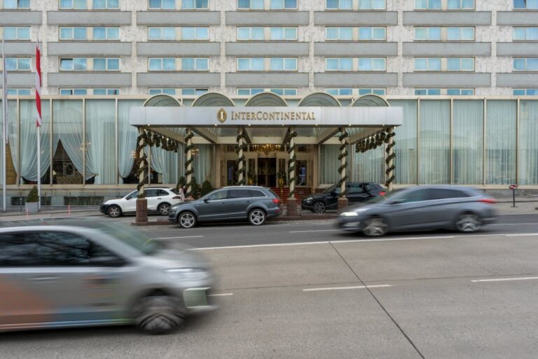 Hotel aus den 1960ern in Wien, davor fahrende und parkende Autos