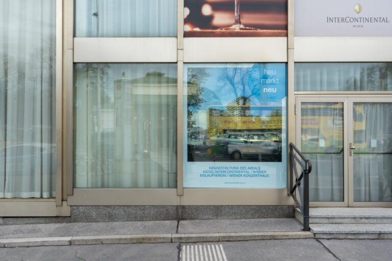 Glasfront im Erdgeschoß eines Hotelgebäudes in Wien, Plakat mit einem Rendering eines Neubaus am Heumarkt