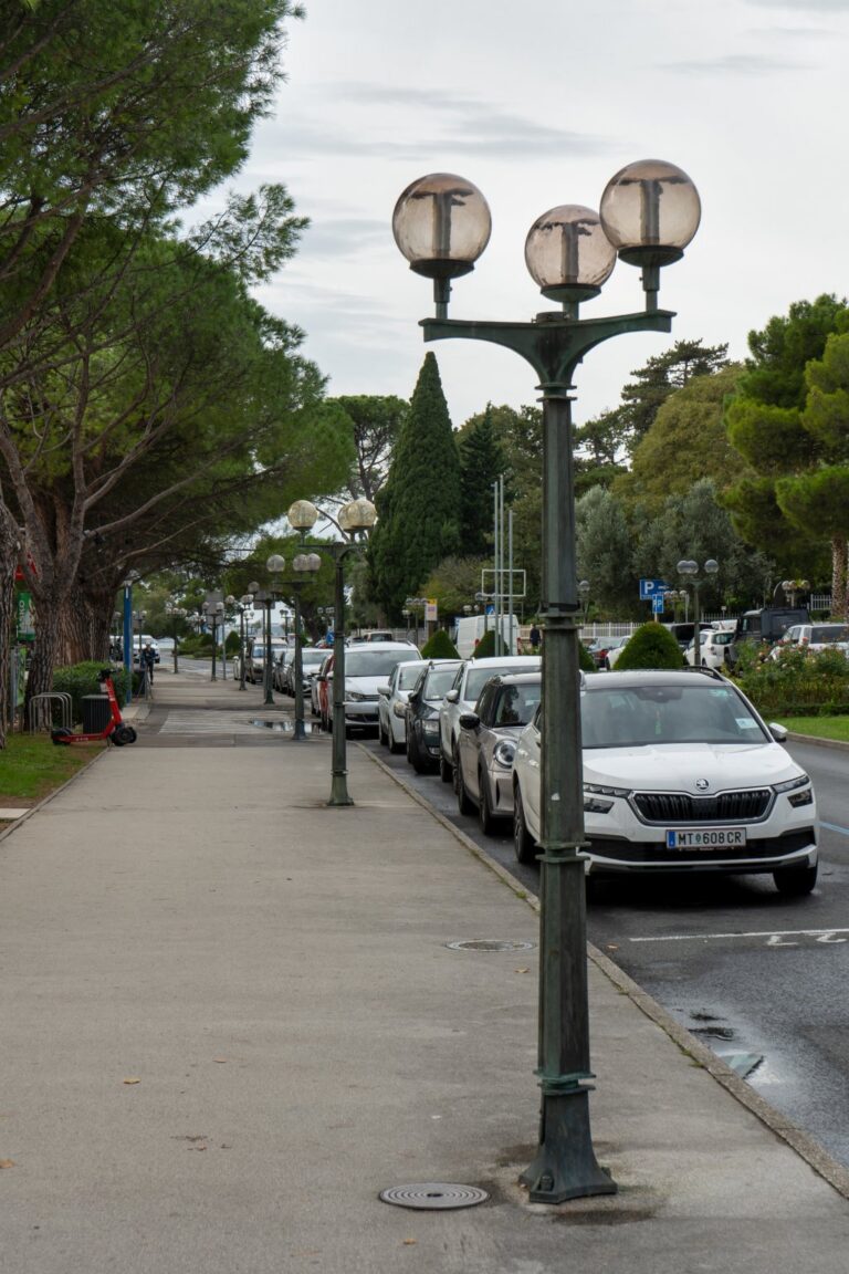 Straßenlaternen, parkende Autos, Gehsteig, Bäume, Slowenien