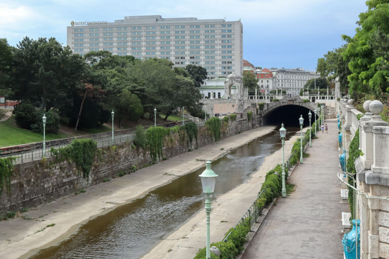 Wienfluss beim Stadtpark, großes Hotelgebäude, Bäume, historische Laternen, Jugendstilarchitektur