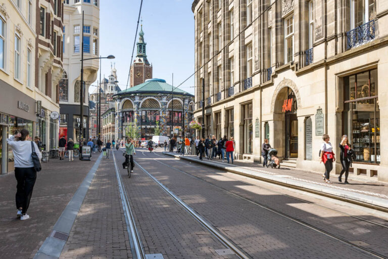 Straße, alte Gebäude, Straßenbahnschienen, Leute am Gehsteig, Radfahrerin