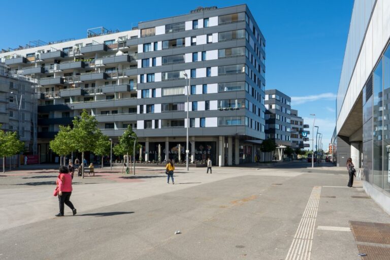 Asphaltfläche und Bäume vor einer modernen Wohnhausanlage in Wien-Donaustadt
