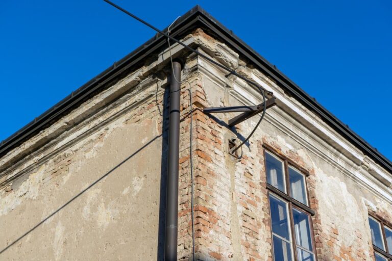 schadhaftes altes Gebäude, Gesims, Kabel, Regenrinne