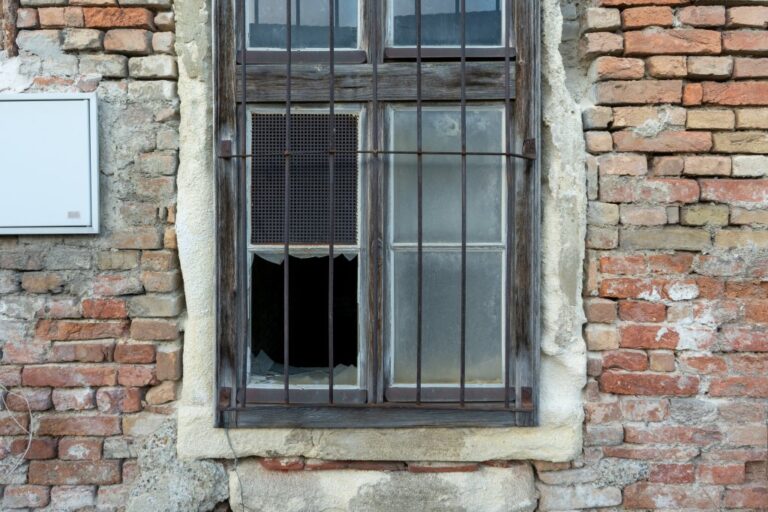 vergittertes Fenster mit fehlender Glasscheibe in einem Nebengebäude von Schloss Neugebäude