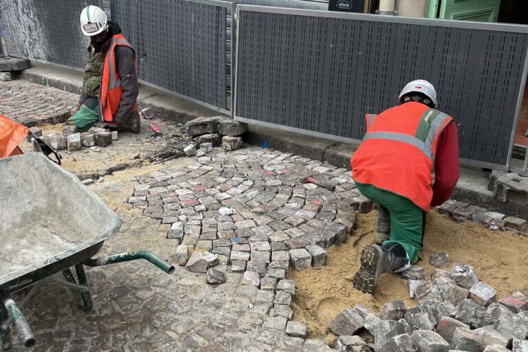 zwei Bauarbeiter verlegen eine Pflasterfläche in Paris