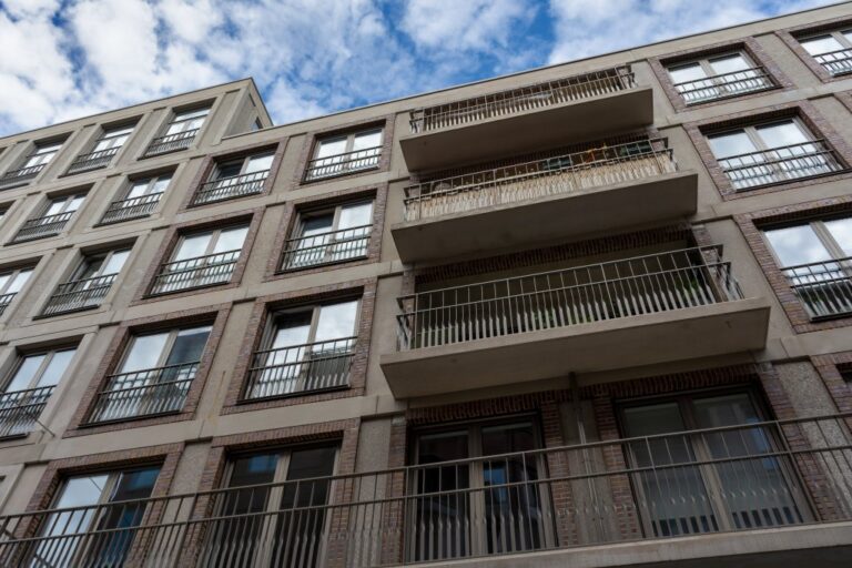 Aufnahme von unten auf die Fassade eines Neubau-Wohnhauses in Utrecht mit Balkonen und großen Fenstern