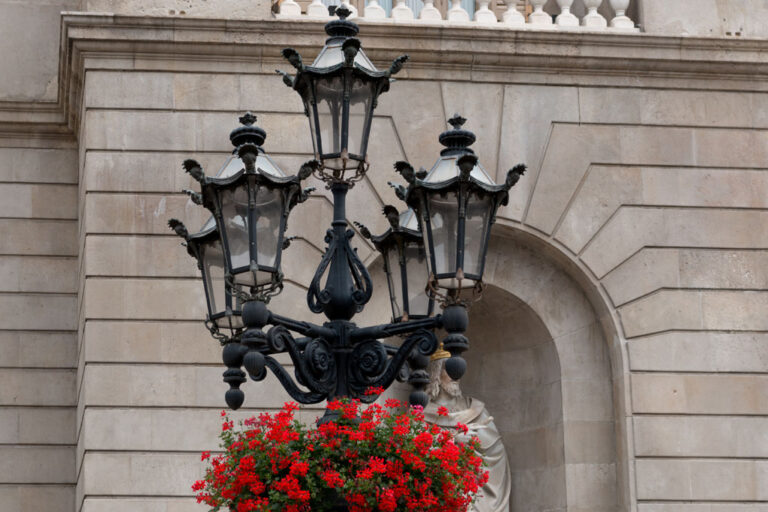 historische Straßenbeleuchtung mit Blumen vor einem alten Gebäude