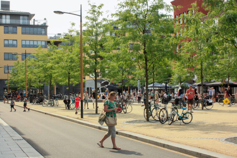 Person geht über einen Platz mit Bäumen, Fahrräder, Stadtentwicklungsgebiet